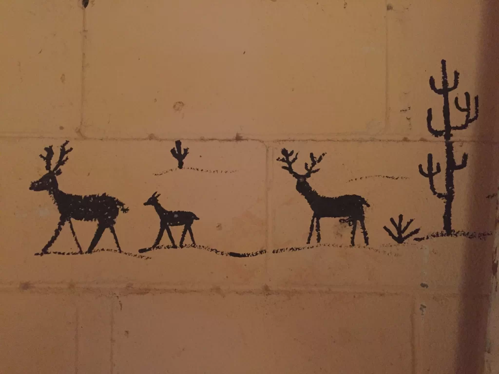 Silueta de venados o ciervos dibujadas en estilo esquemático sobre una superficie de tono ocre